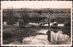 Front: Women doing washing at a small rive...